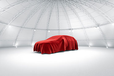 car hidden under a red covering awaiting unveiling in a showroom