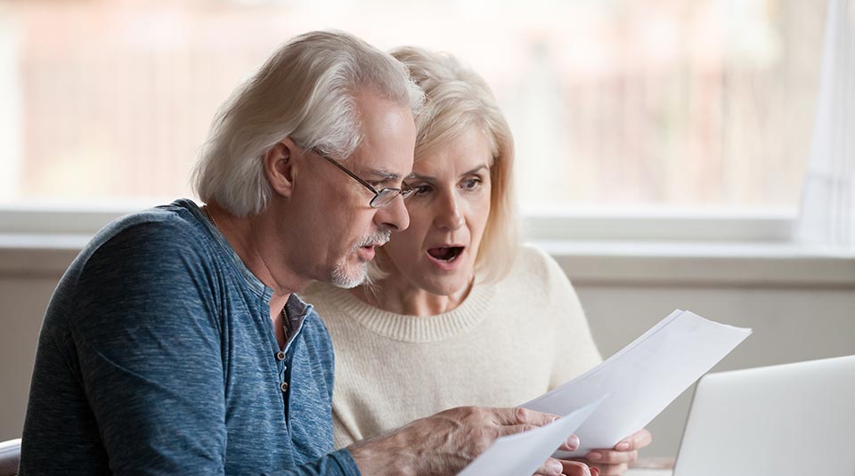 elderly couple looking at a letter in shock