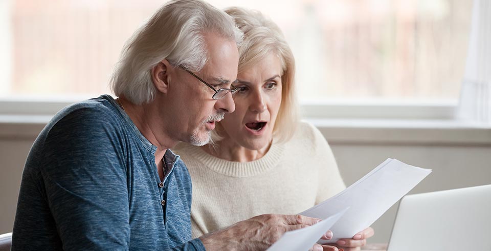 a couple looking surprised at a letter in the post