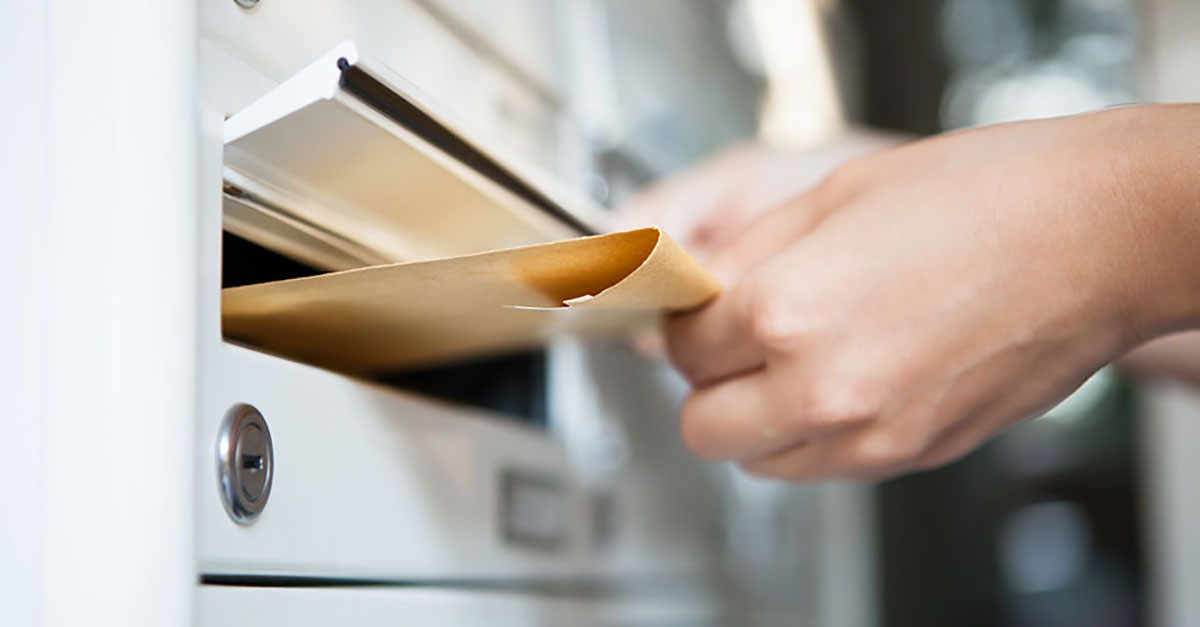 direct mail being hand delivered into a letter box