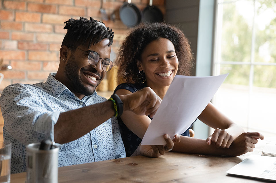 couple opening a letter and looking happy at what she is reading