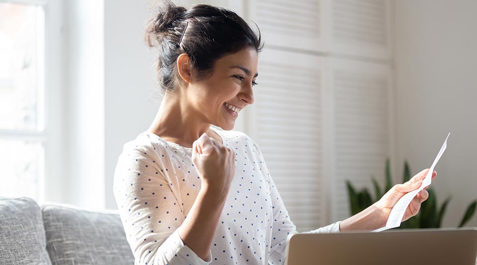 woman opening a letter and looking happy at what she is reading